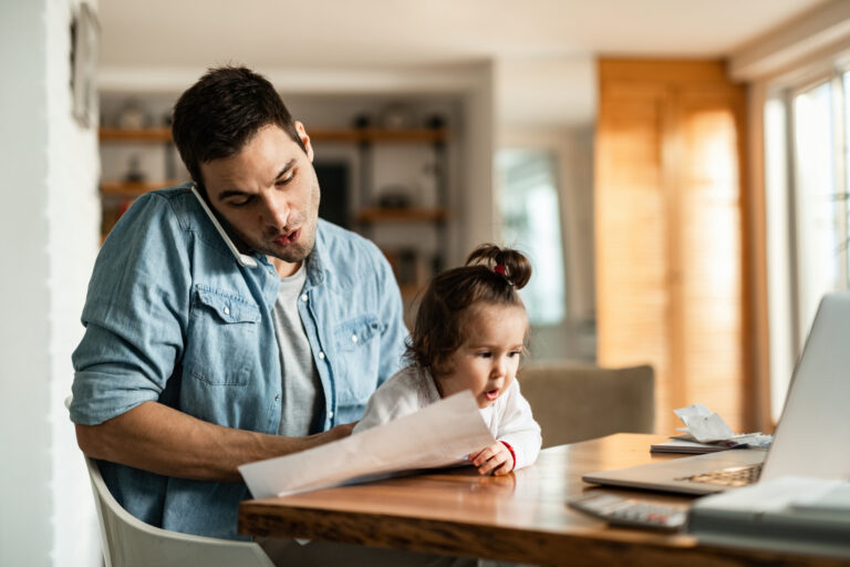 young father with daughter talking on the phone while working at