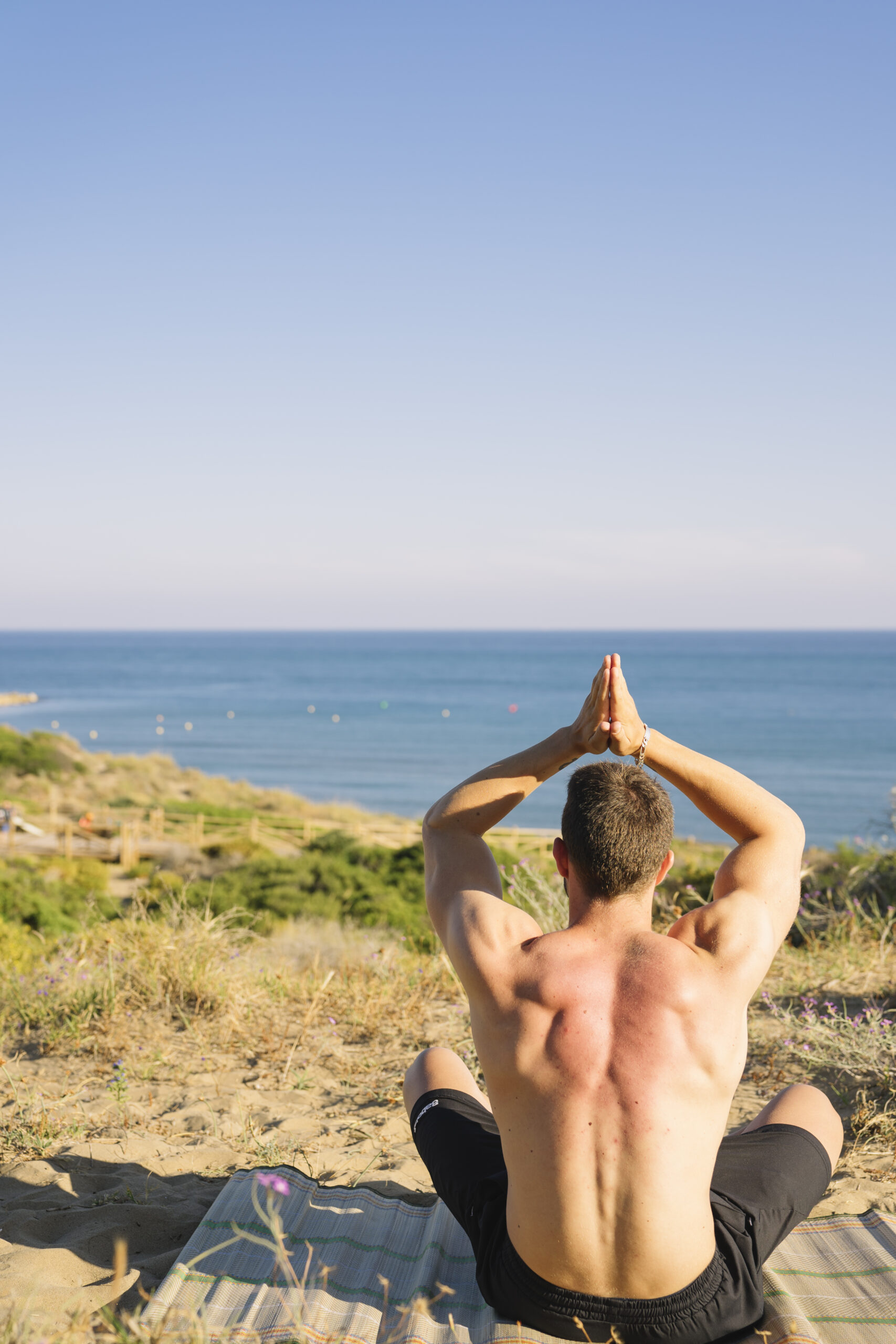 man doing yoga looking towards sea