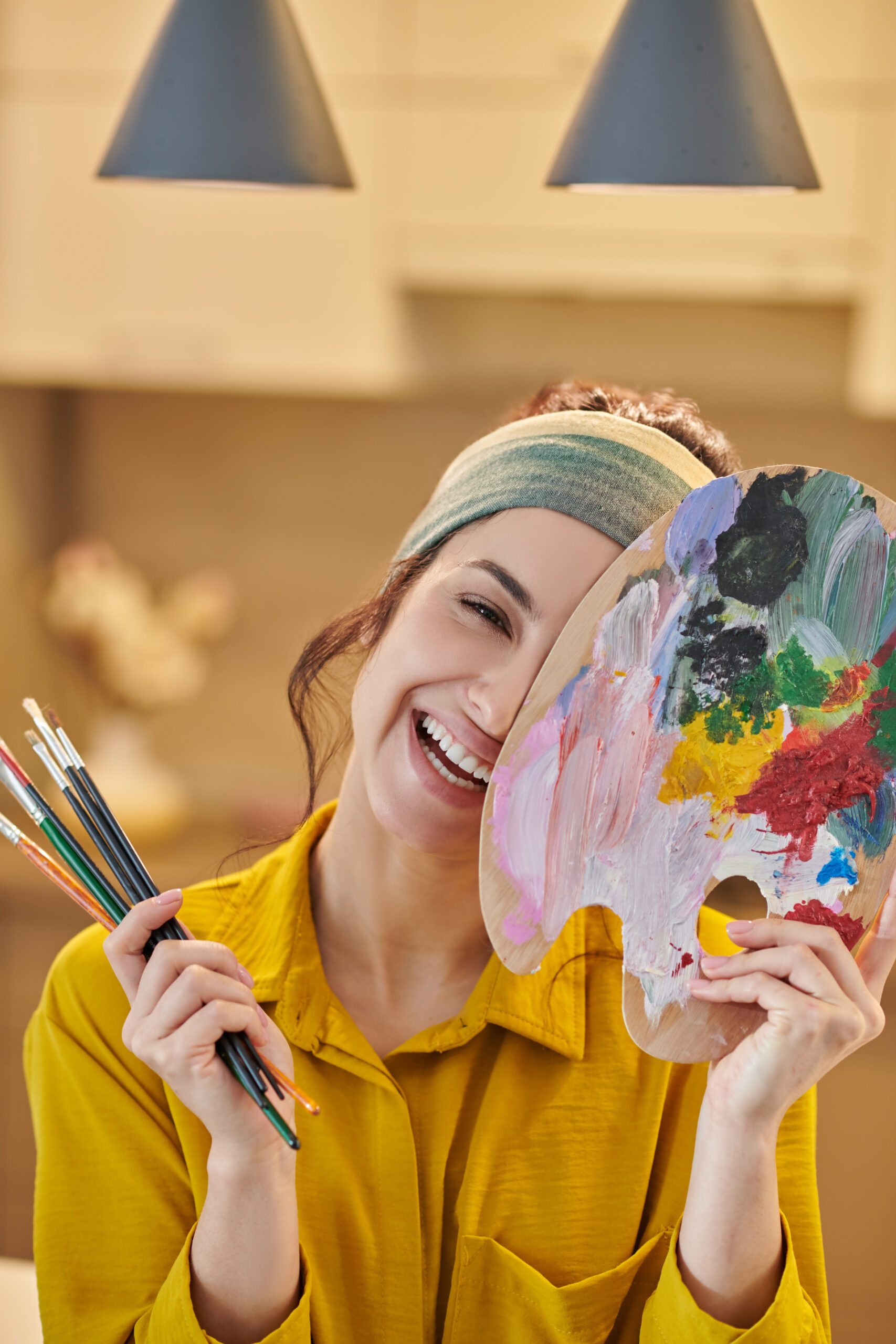 a pretty young woman with a palette and brushes in hands