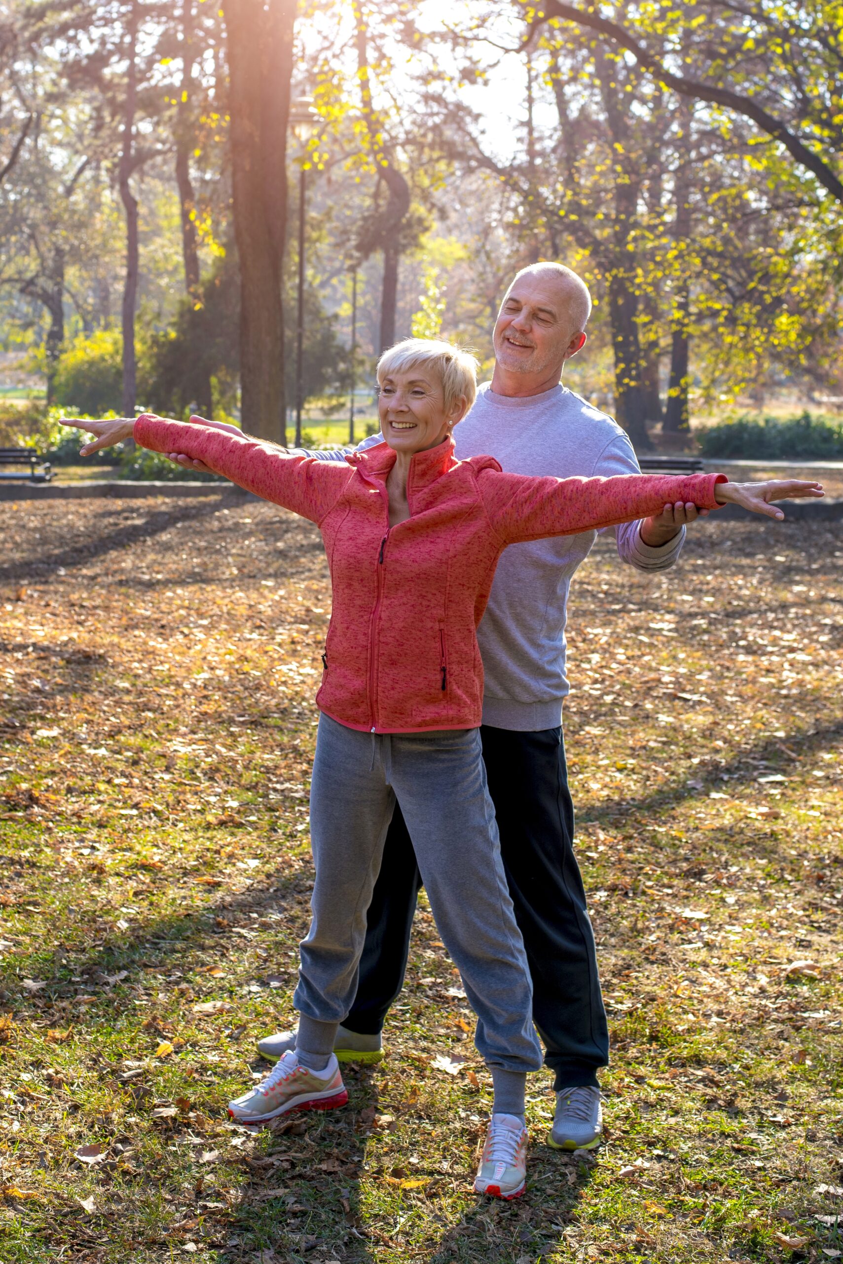 senior male and a female exercising together in the park in autumn