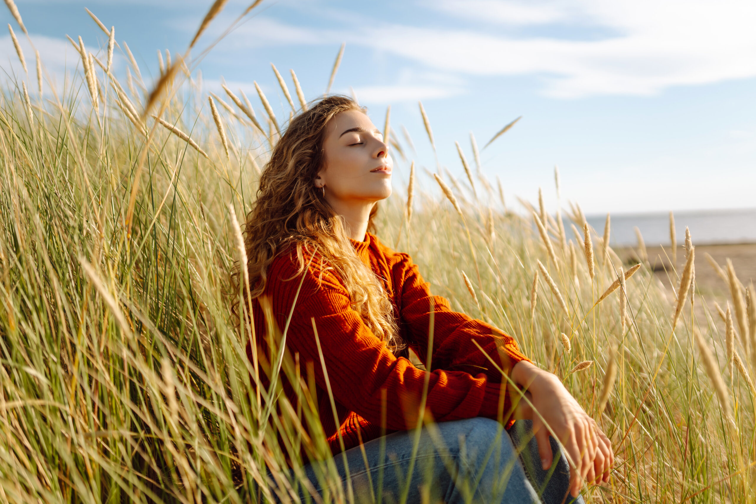 beautiful young woman enjoying nature outdoors in tall grass. flying hairs. lifestyle. fashion style
