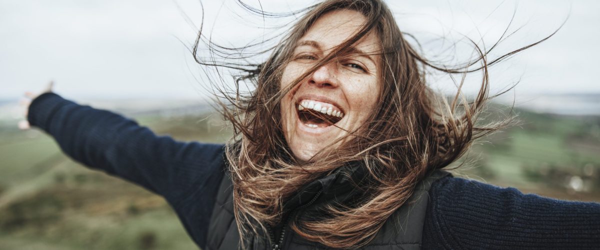 smiling woman spreading arms, outdoor activity